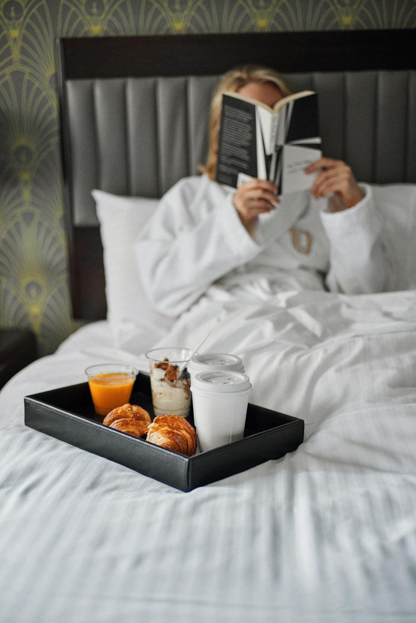 Hotel Edison Times Square Нью-Йорк Екстер'єр фото A woman reading a book while lying in bed.